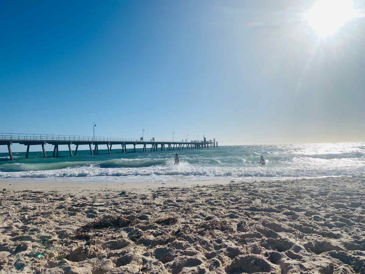 Sunny day at Glenelg Beach with the jetty extending over sparkling turquoise waters, a relaxing spot on any South Australia itinerary.