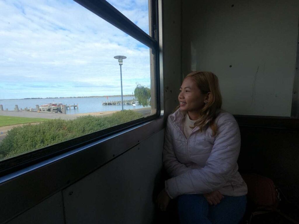 The author, Kate, seated inside the Cockle Train looking out towards the calm waters and jetty of the Adelaide Hills, contemplating the serene things to do in the region.