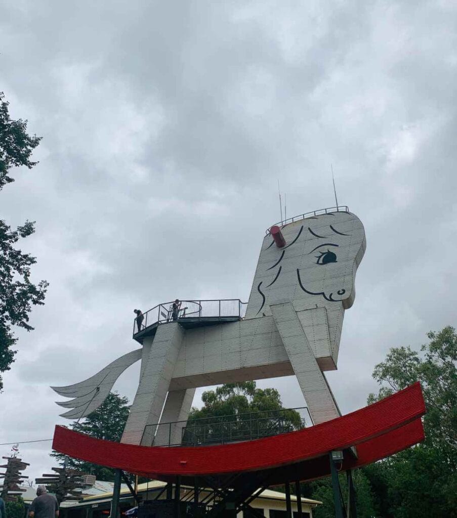 Visitors atop the iconic Gumeracha Big Rocking Horse, a unique and quirky attraction among the things to do in the Adelaide Hills, under a cloudy sky.