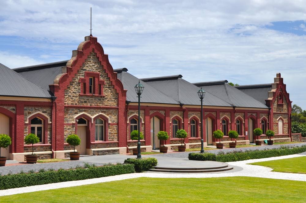 The historic Chateau Tanunda building in Barossa Valley, featuring traditional architecture with red brick and stonework under a partly cloudy sky. This iconic winery is part of the broader map of Barossa Valley wineries, illustrating the region's rich heritage and significance in the blog post.