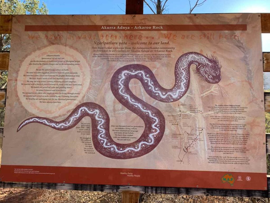 An interpretive sign at Arkaroo Rock in the Flinders Ranges, featuring a detailed illustration of an Akurra serpent and traditional Adnyamathanha stories. This site is a must-visit historical site in the outback, showcasing the cultural significance and ancient rock art of the Adnyamathanha people.