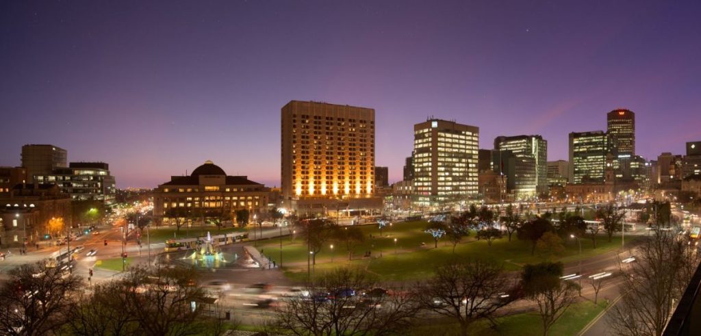 Twilight view of Victoria Square / Tarntanyangga in Adelaide, with city lights illuminating surrounding heritage buildings and modern offices. This central hub is one of the most historically significant places in Adelaide, originally a Kaurna meeting ground and now a lively civic space blending past and present.